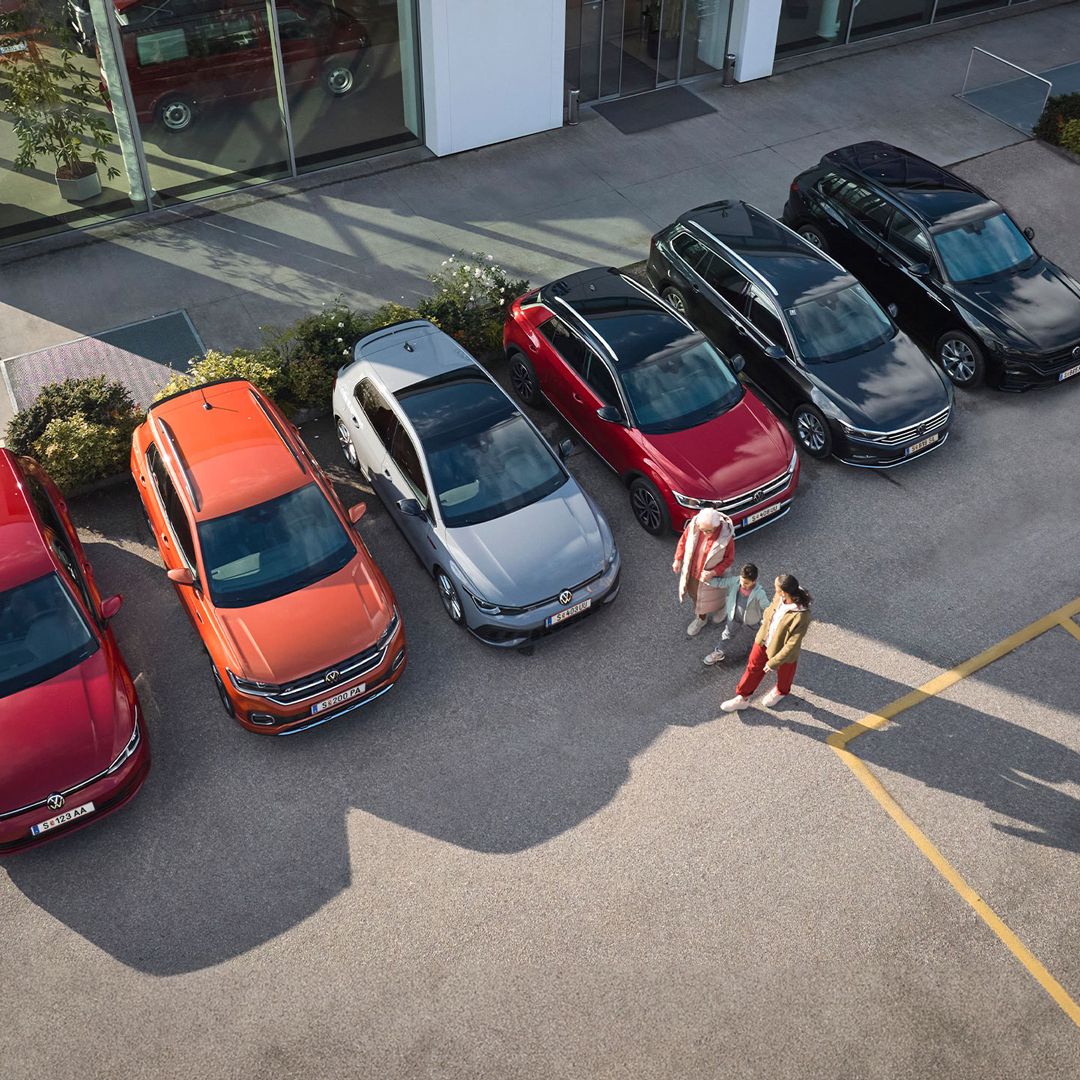 Eine Familie geht neben sechs Vorgängermodellen an einem Autohaus vorbei
