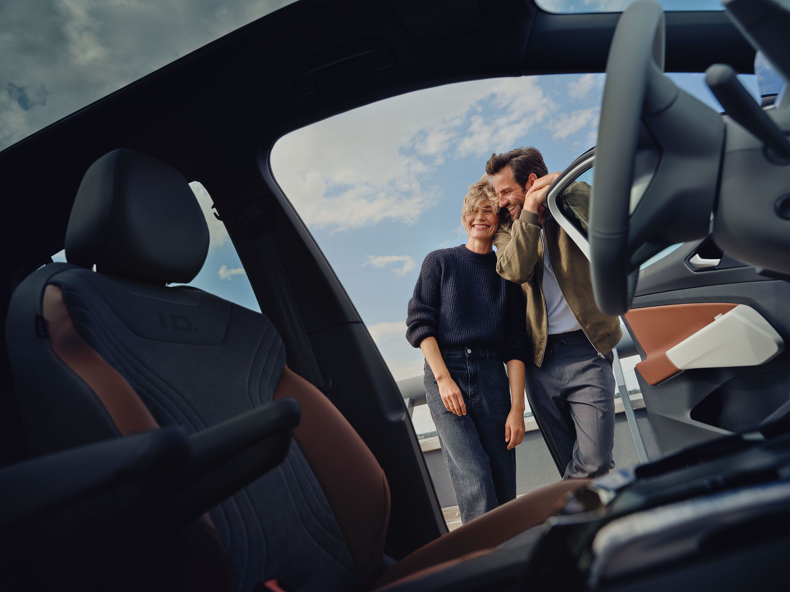 Blick aus dem Cockpit eines Volkswagen, ein Mann und eine Frau stehen außerhalb des Fahrzeuges