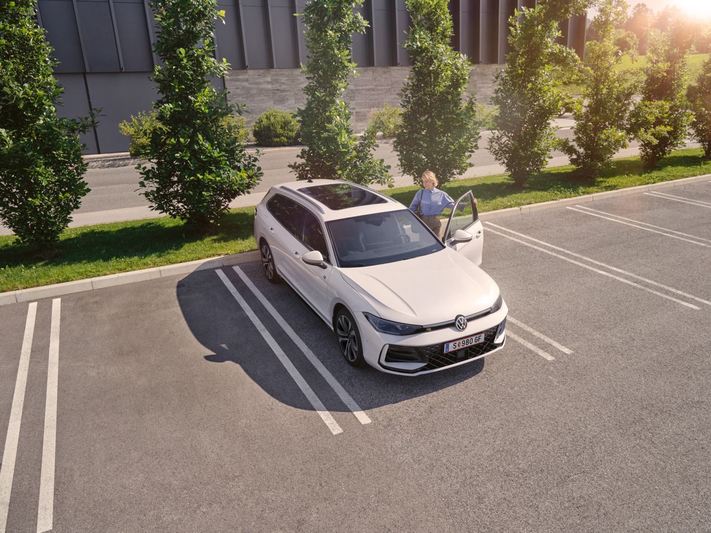 Weißer VW Passat parkt vor einem modernen Bürogebäude. Eine Frau steigt ein.
