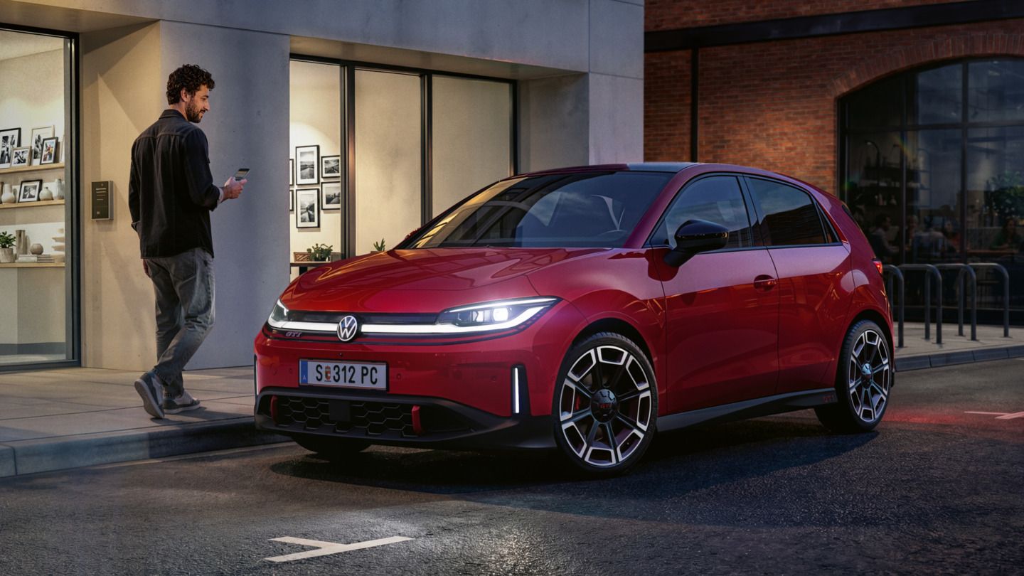 Eine Person geht an einem roten VW ID. Polo GTI vorbei, der vor einem modernen Gebäude parkt.