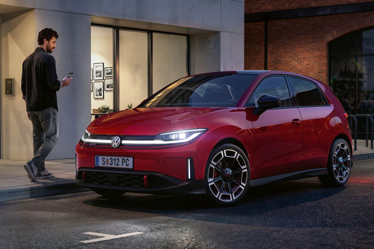 Eine Person geht an einem roten VW ID. Polo GTI vorbei, der vor einem modernen Gebäude parkt.