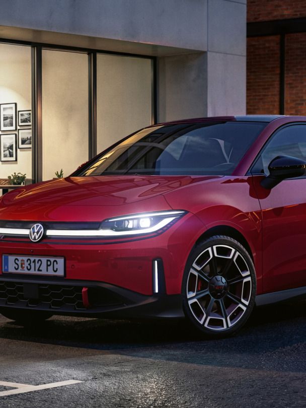 Eine Person geht an einem roten VW ID. Polo GTI vorbei, der vor einem modernen Gebäude parkt.
