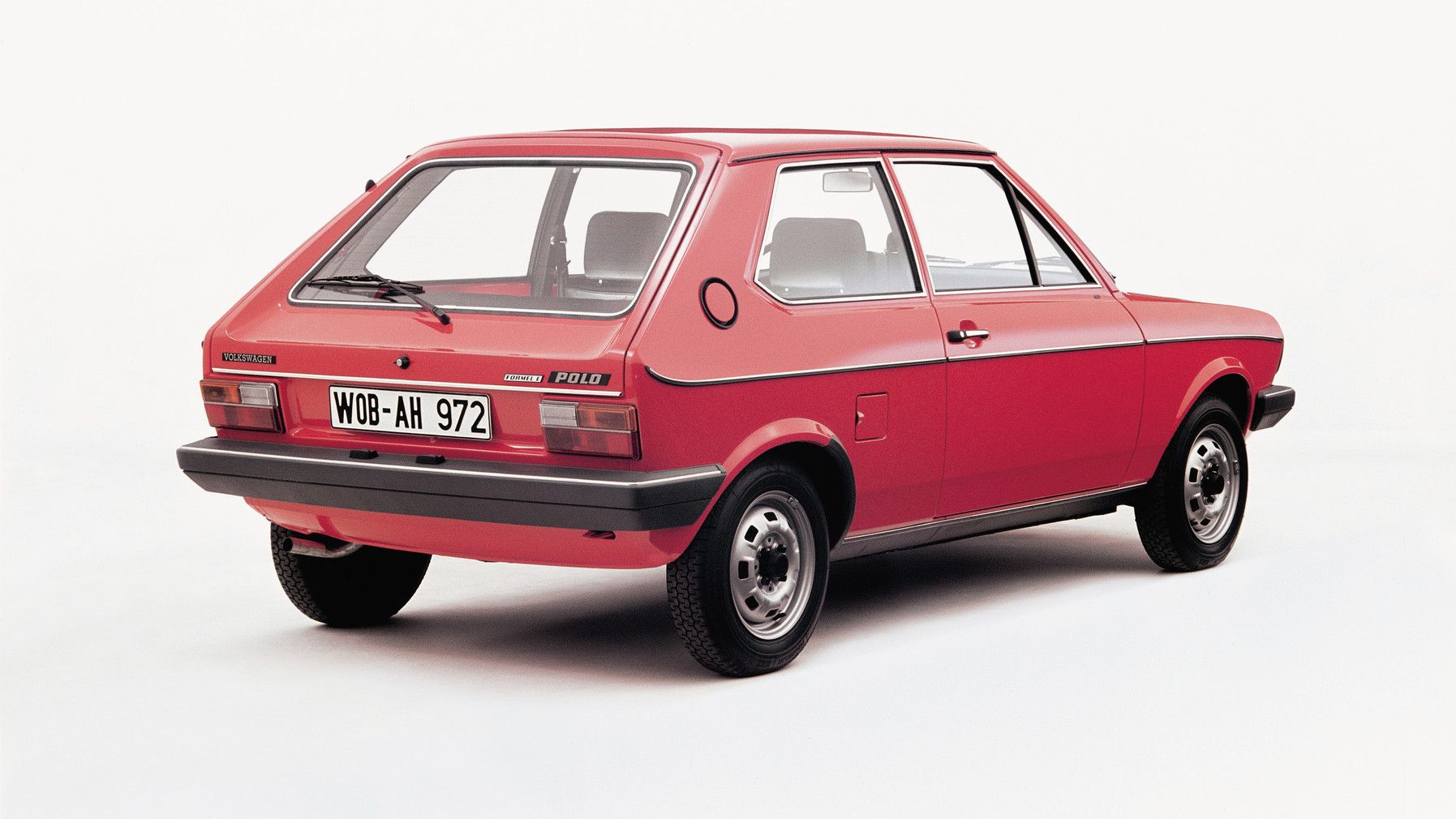 Ein roter VW Polo, von hinten fotografiert auf weißem Hintergrund. Das Fahrzeug hat zwei Türen und ist mit einem Kennzeichen WOB-AH 972 versehen.