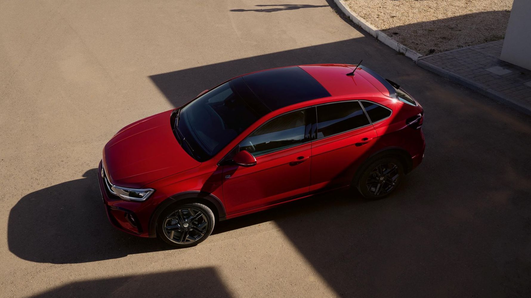 Blick von oben auf einen roten VW Taigo mit Panorama-Ausstell-/Schiebedach.