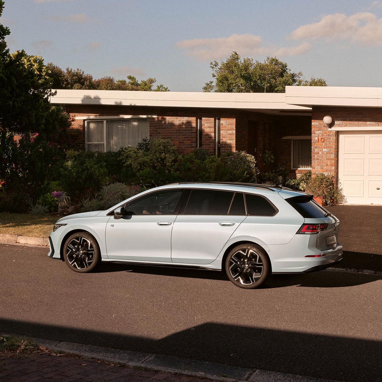 Seitenansicht eines VW Golf Variant in der Farbe Ice Blue Metallic geparkt vor Einfamilienhaus