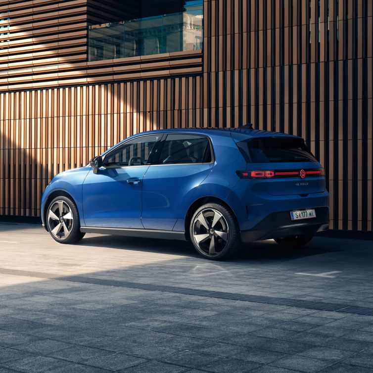Ein blauer VW ID. Polo Style steht vor einem Gebäude mit Holzfassade.
