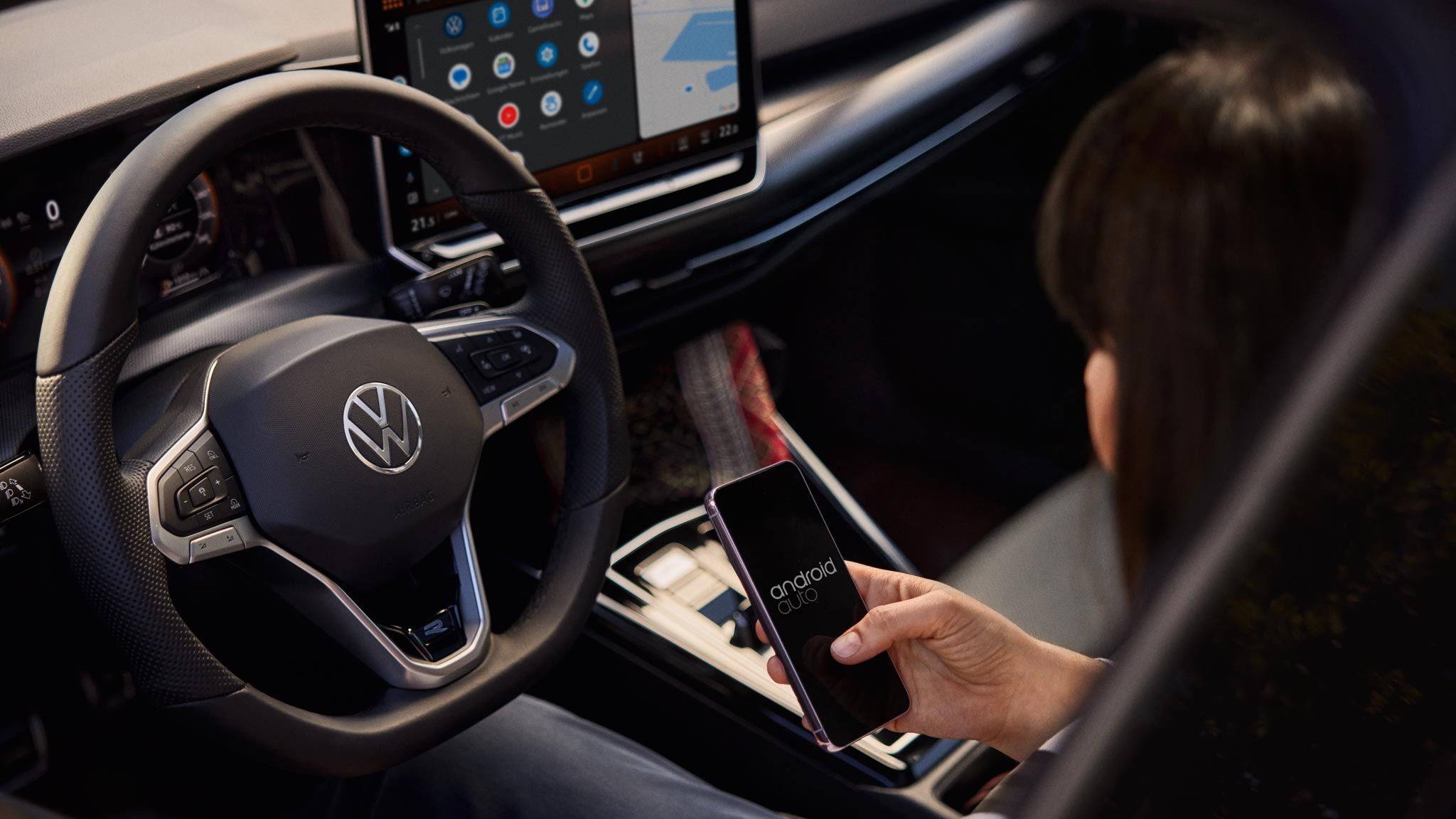 Frau sitzt im VW Golf Variant und nutzt Wireless App-Connect mit ihrem Smartphone