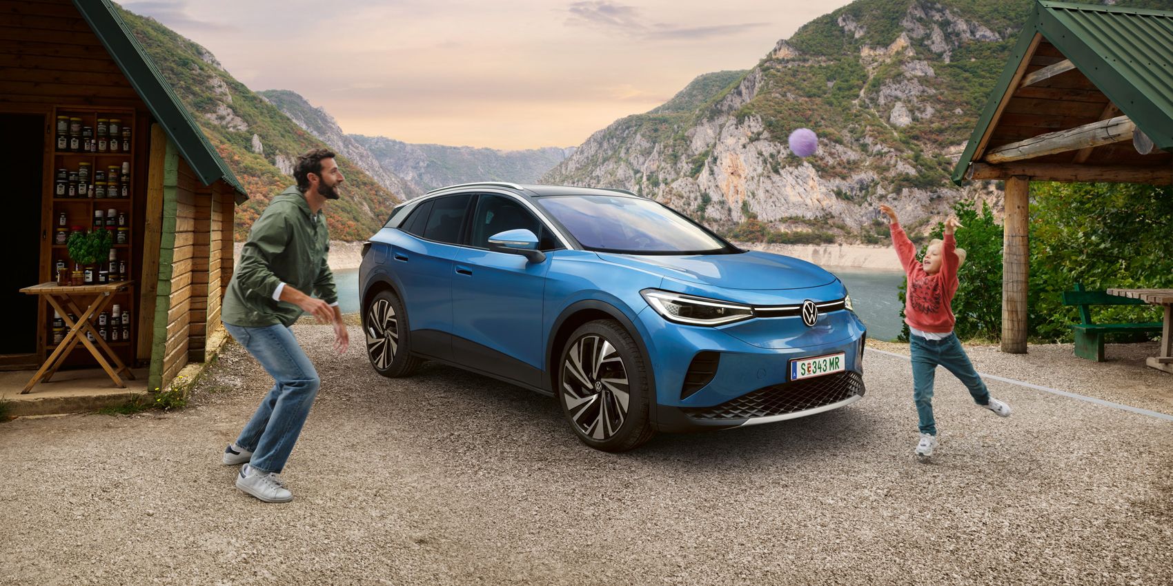 Vater und Sohn spielen mit einem Ball, dahinter steht ein blauer VW ID.4.