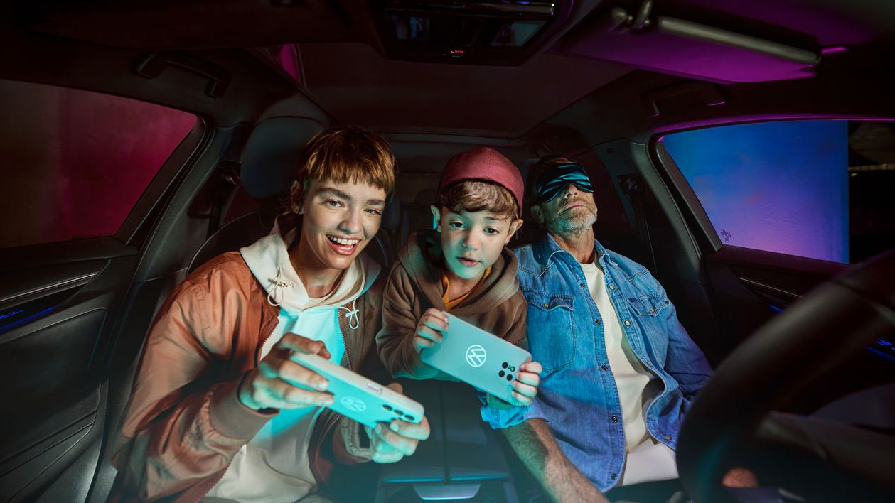 Vater mit zwei Kindern im Volkswagen, die Kinder spielen mit der AirConsole.