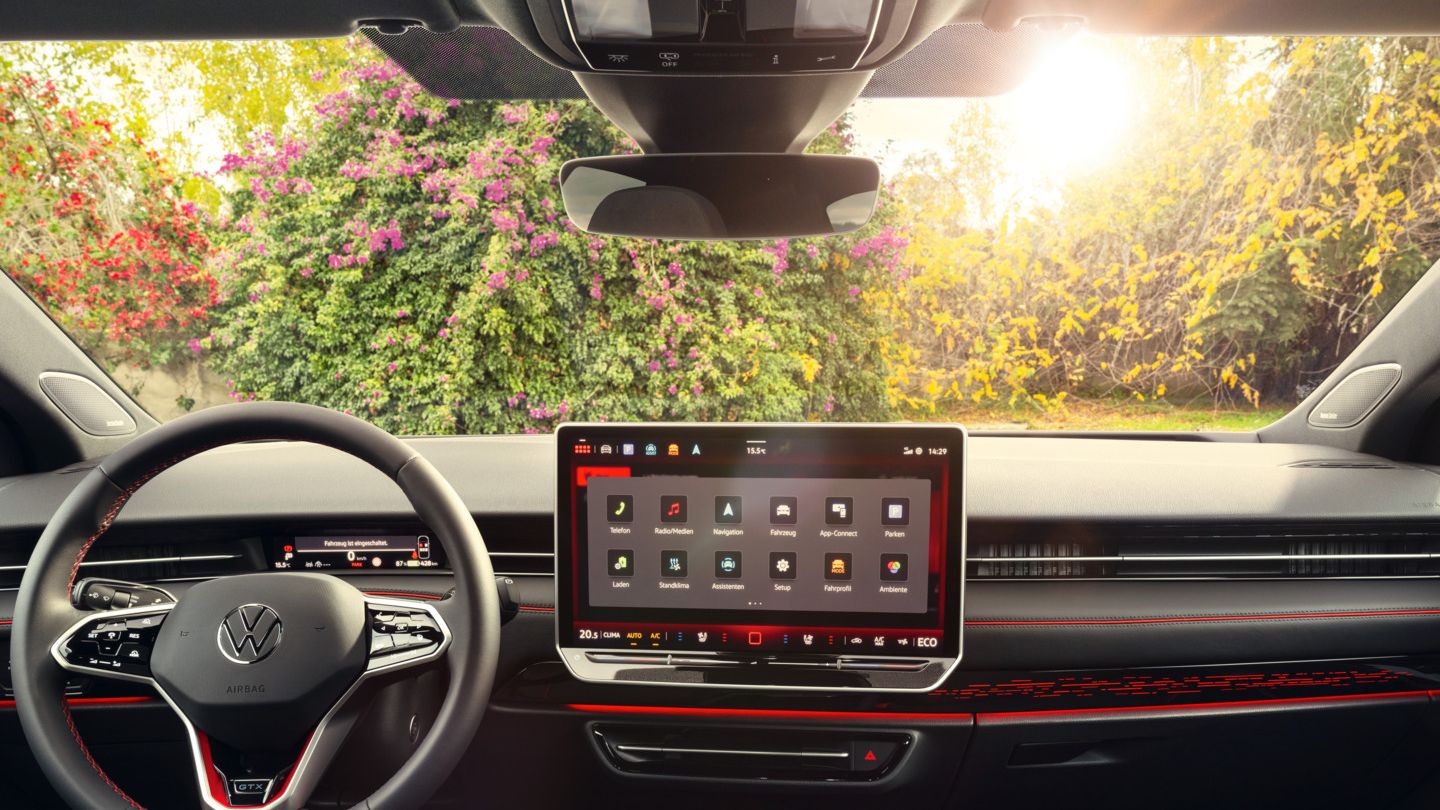 Cockpit eines VW ID.7 GTX mit Multifunktionslenkrad und Infotainmentsystem mit roten Akzenten.