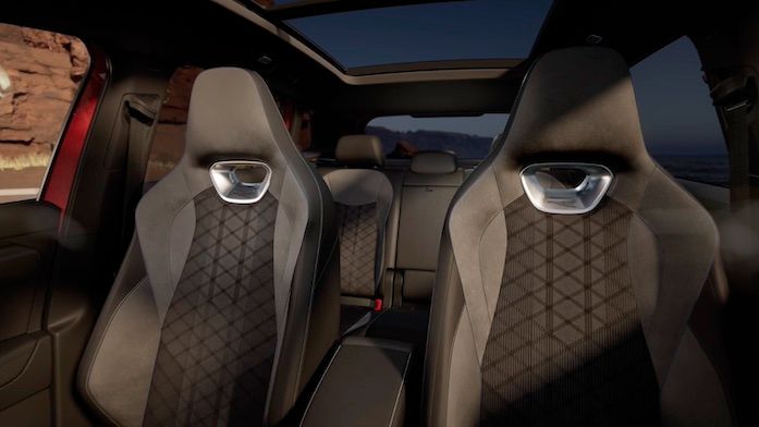 Das Bild zeigt den Innenraum von einem Tiguan. Es sind zwei vordere Sitze mit auffälligen Mustern an der Rückenlehne zu sehen. Das Auto hat ein großes Glasdach, durch das Sonnenlicht einfällt.