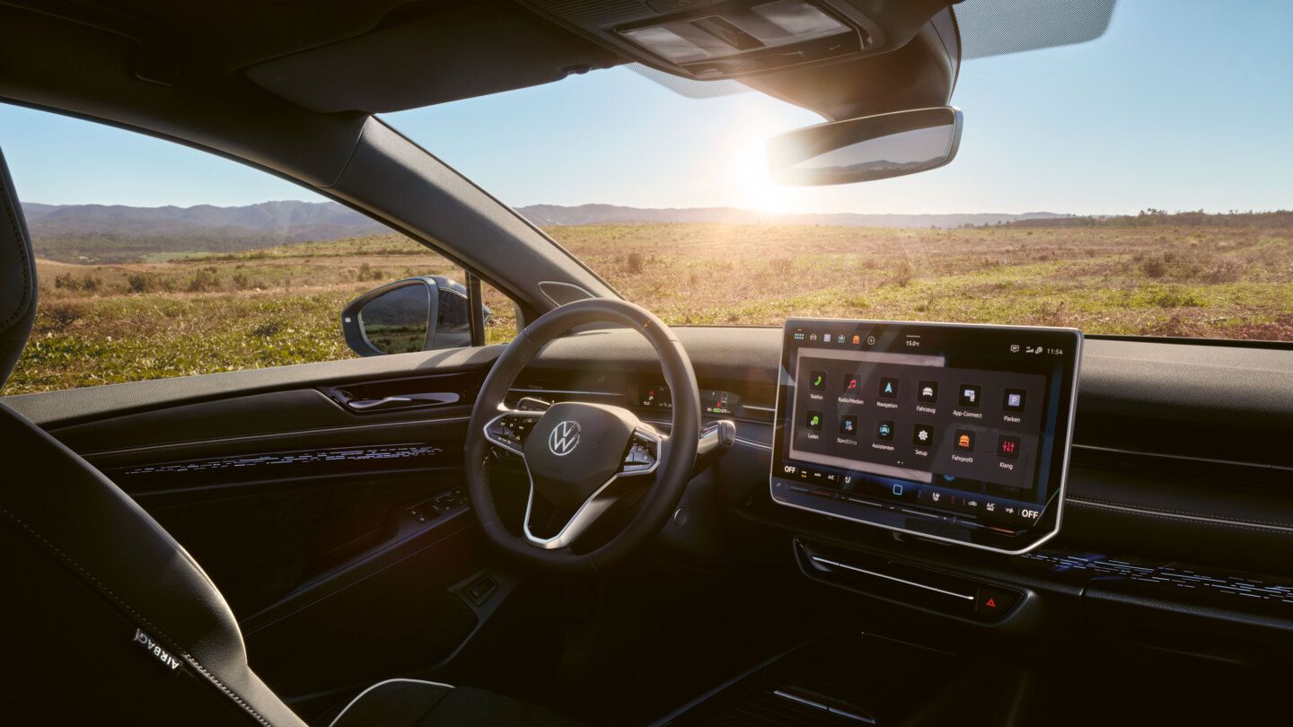 Interieur des ID.7 Tourer mit Ambientebeleuchtung, Infotainmentsystem und Multifunktionslenkrad. 