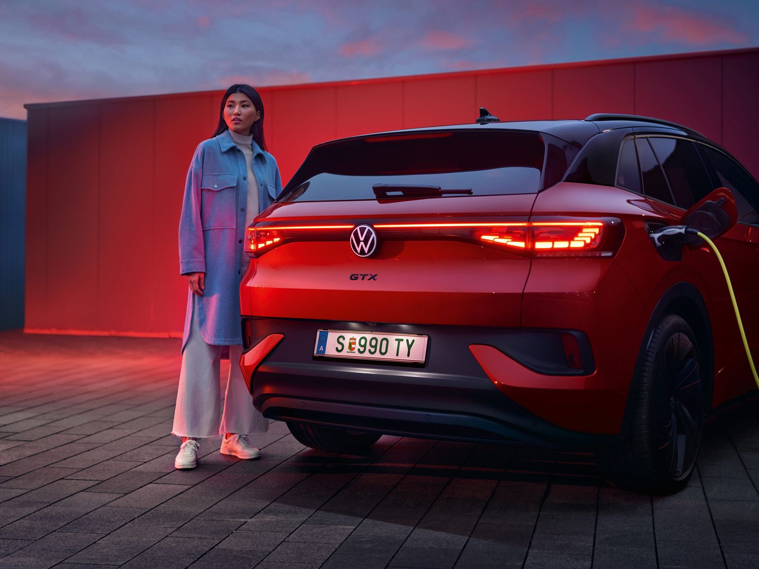 Heckansicht des VW ID.4 GTX 4MOTION, eine Frau steht daneben