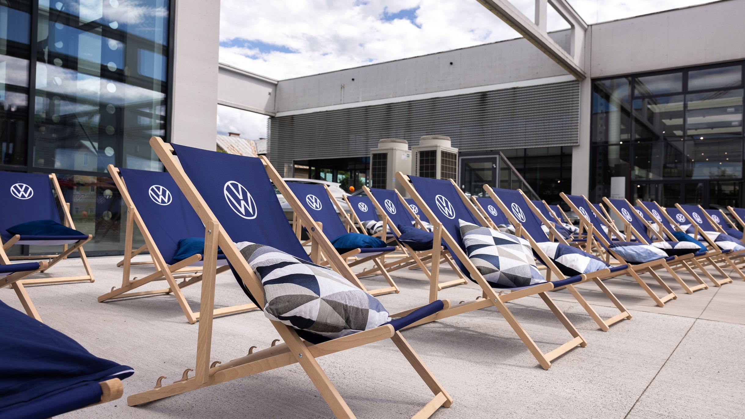 Aufgestellte VW Liegestühle mit Kissen in drei Reihen.