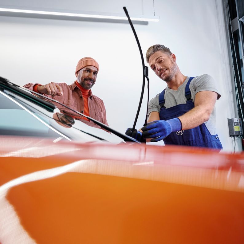 Ein VW Service Techniker wechselt Wischerblätter bei einem Volkswagen