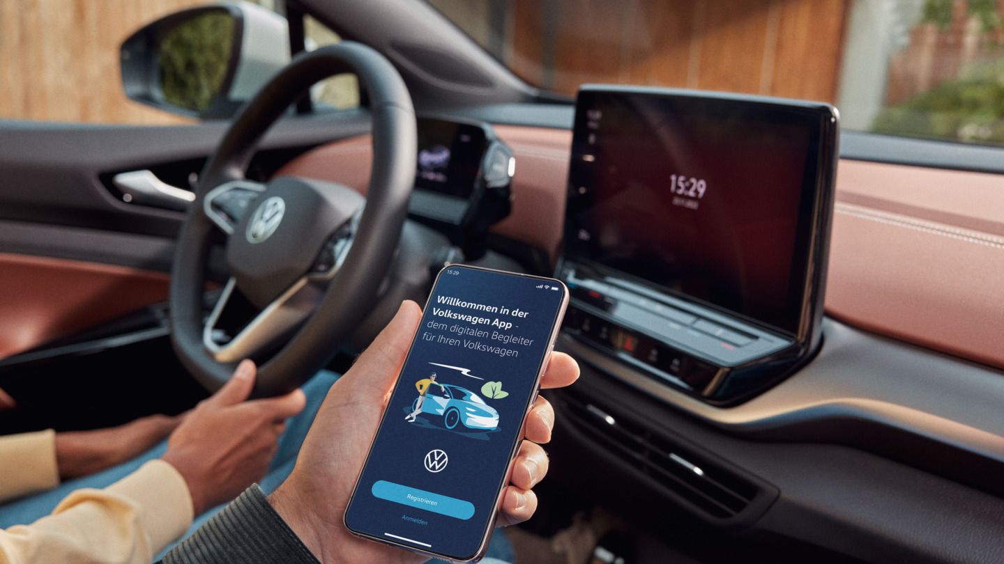 Zwei Personen sitzen vorne im ID.5 und nutzen die Volkswagen App auf dem Smartphone.