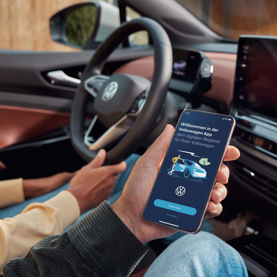 Zwei Personen sitzen vorne im ID.5 und nutzen die Volkswagen App auf dem Smartphone.