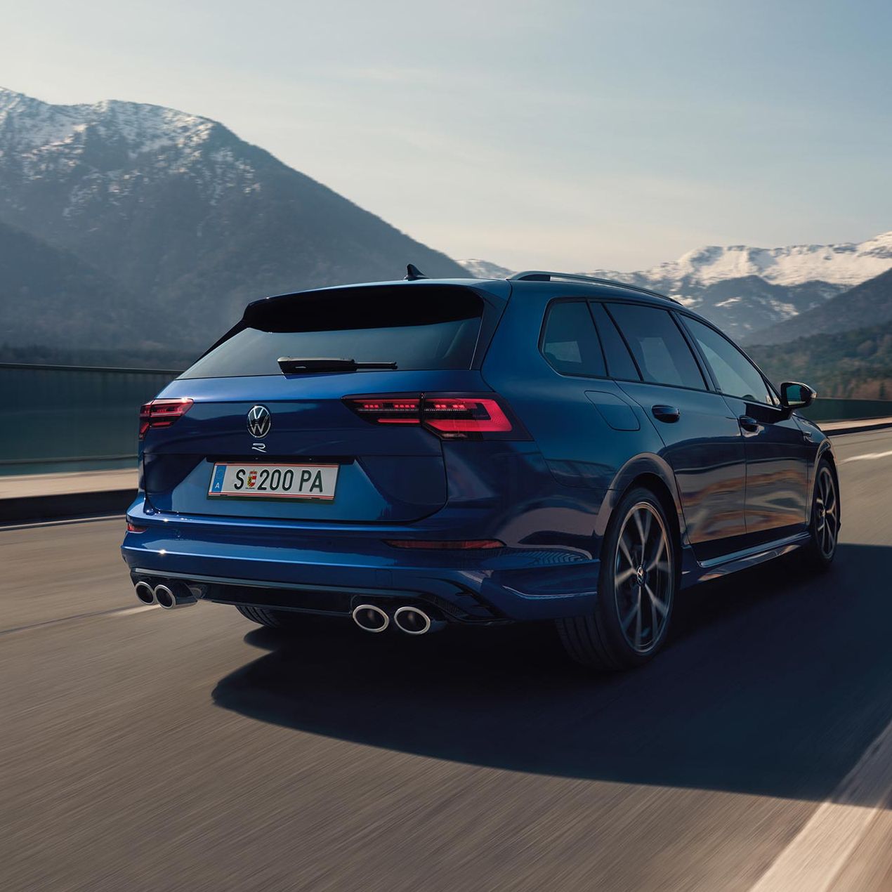Ein blauer Golf Variant R fährt auf einer Straße durch die Berge 