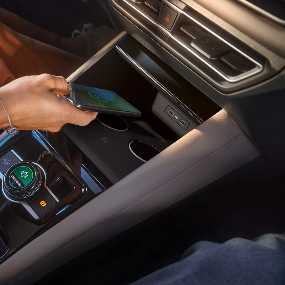 Person legt Smartphone in Ablage für Wireless Charging im VW Tiguan