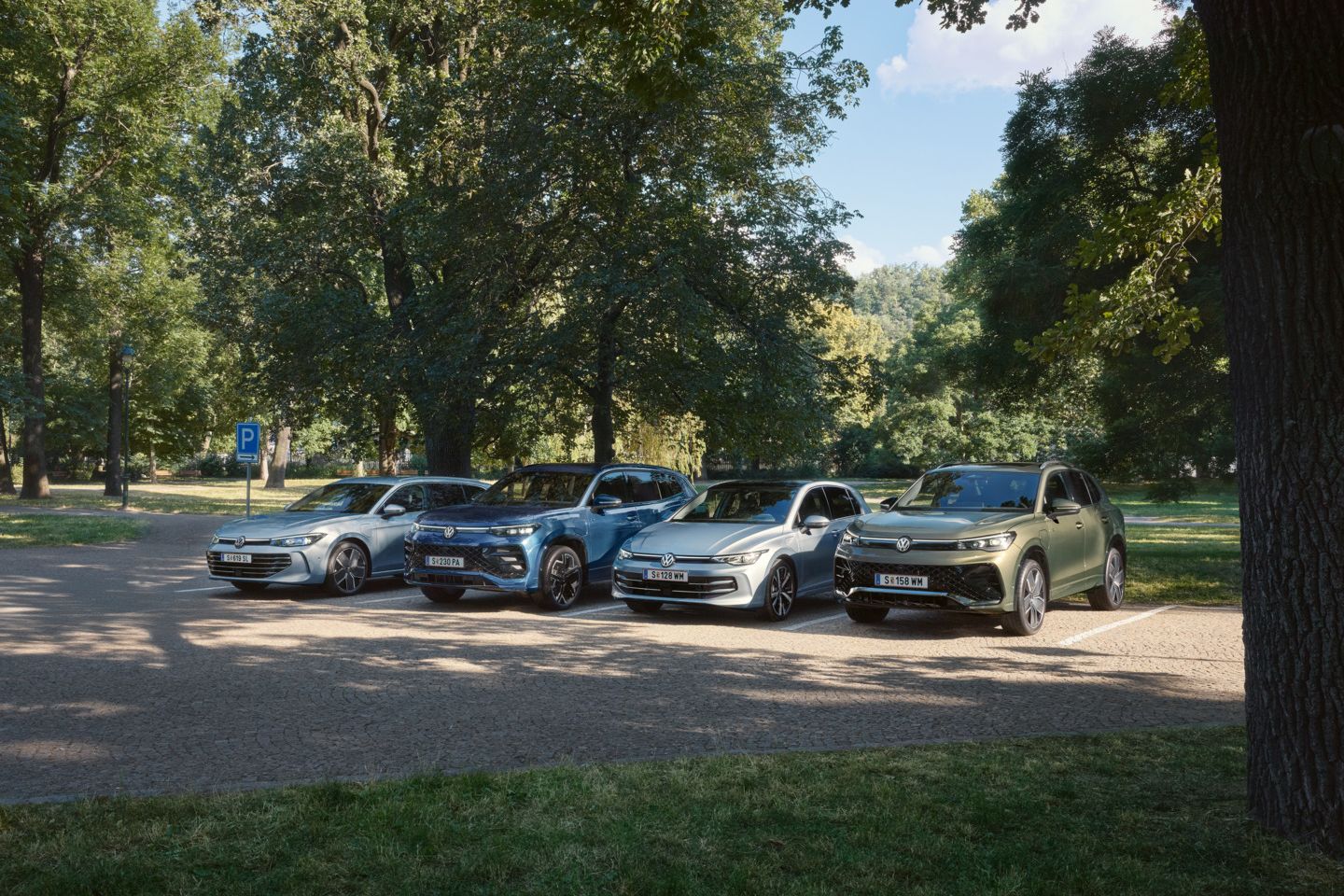 Vier VW Plug-In-Hybrid-Modelle stehen nebeneinander auf einem Parkplatz in einem Park.