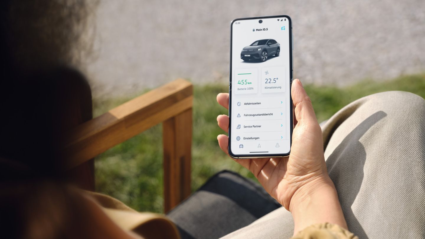 Eine Frau hält ein Smartphone in der Hand und nutzt die VW Connect App.