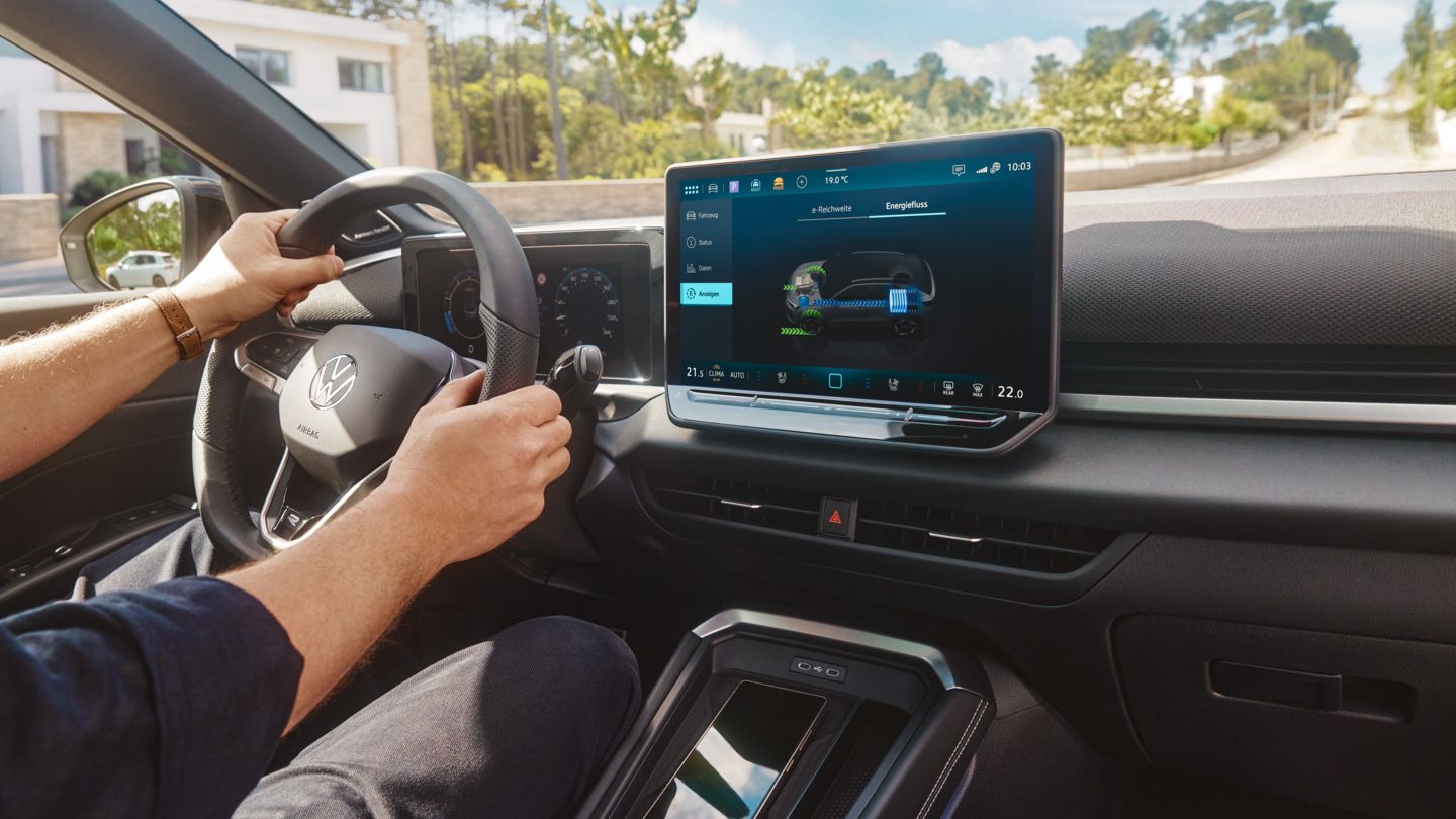Multifunktionslenkrad und Infotainmentsystem im VW T-Roc Hybrid, Person lenkt das Fahrzeug.