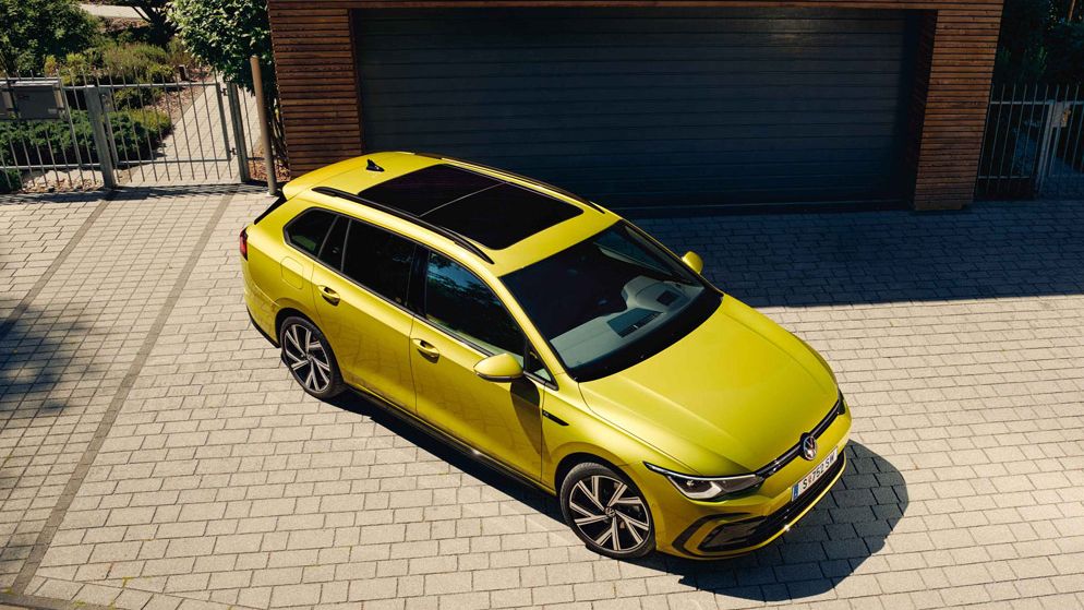 Ein gelber VW Golf Variant steht vor einer Garage
