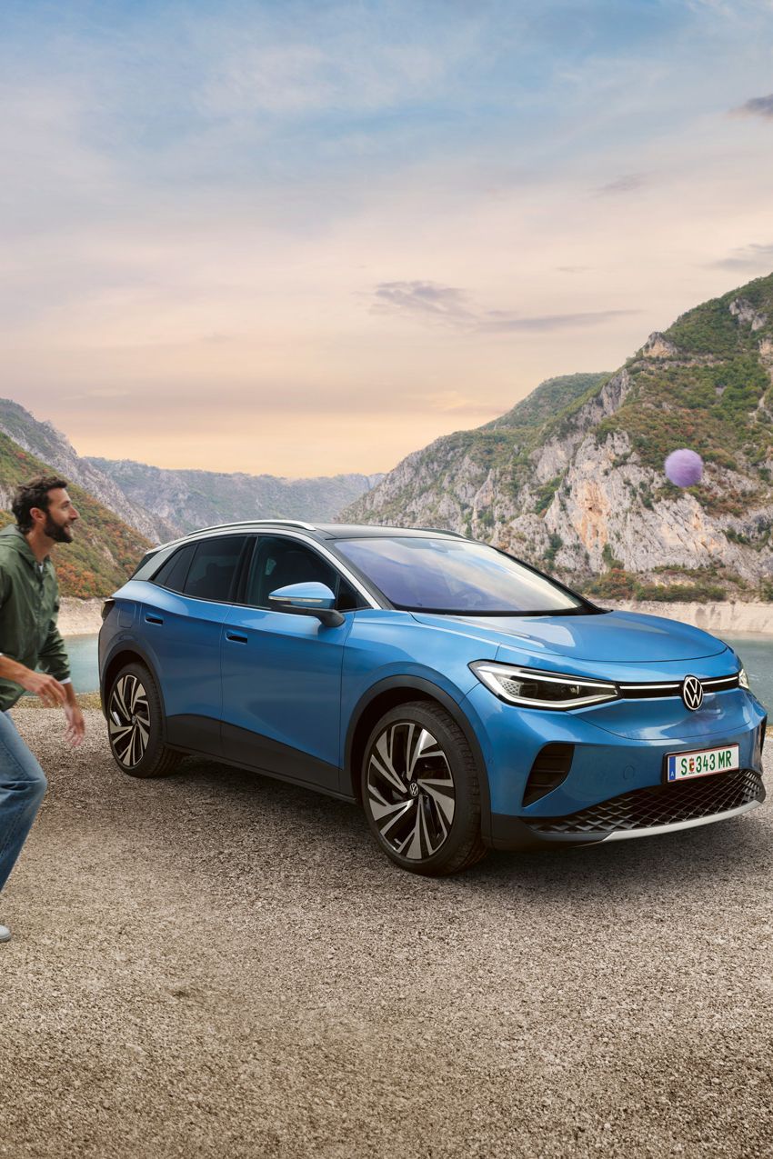 Vater und Sohn spielen mit einem Ball, dahinter steht ein blauer VW ID.4.