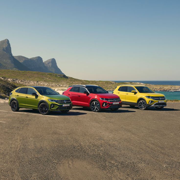 Taigo, T-Roc, T-Cross stehen geparkt auf einem Parkgelände, im Hintergrund sieht man das Meer.