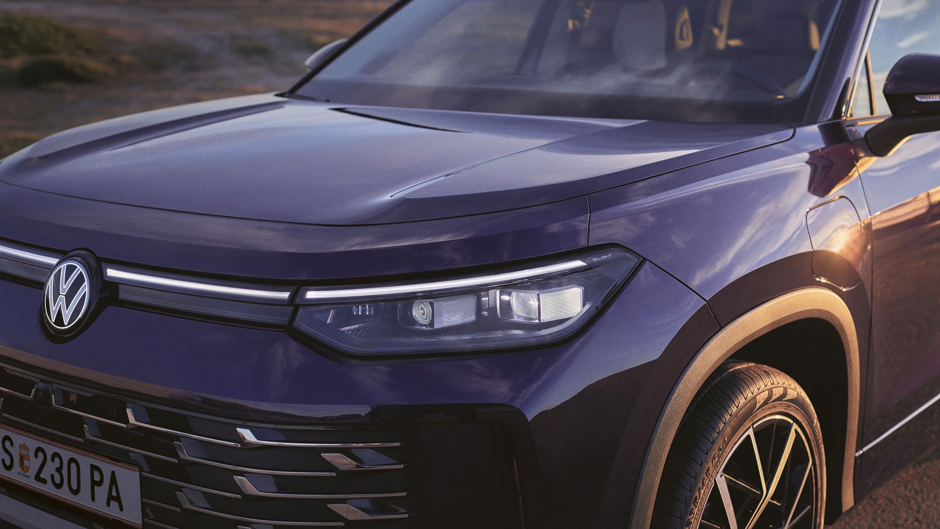 Detailansicht eines VW Tayron mit Front-Lichtsignatur und beleuchtetem VW-Logo.