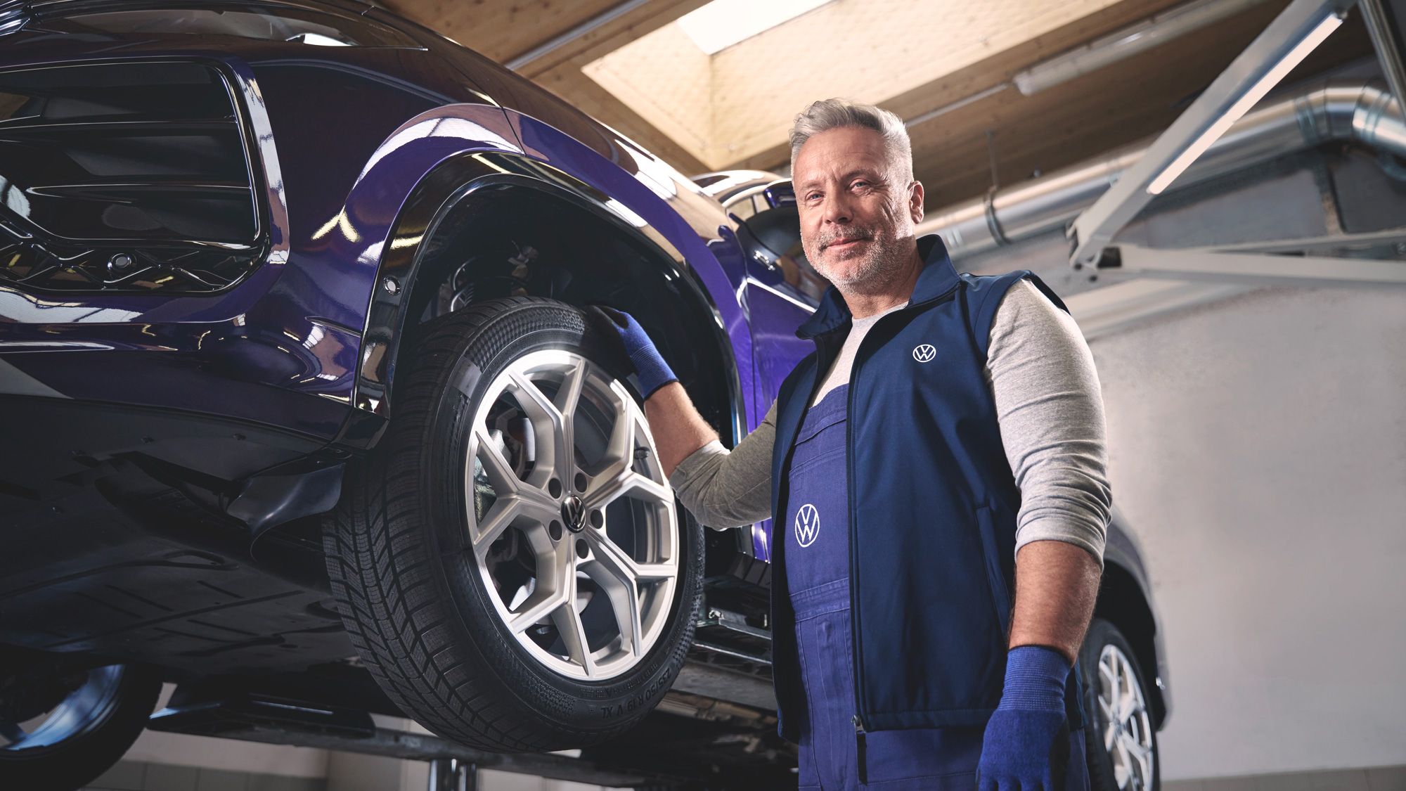 Ein Volkswagen Mechaniker wechselt die Räder bei einem Volkswagen Tayron.