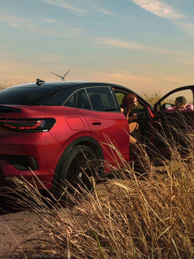 Zwei Personen unterhalten sich neben einem roten ID.5 GTX auf einer Landstraße