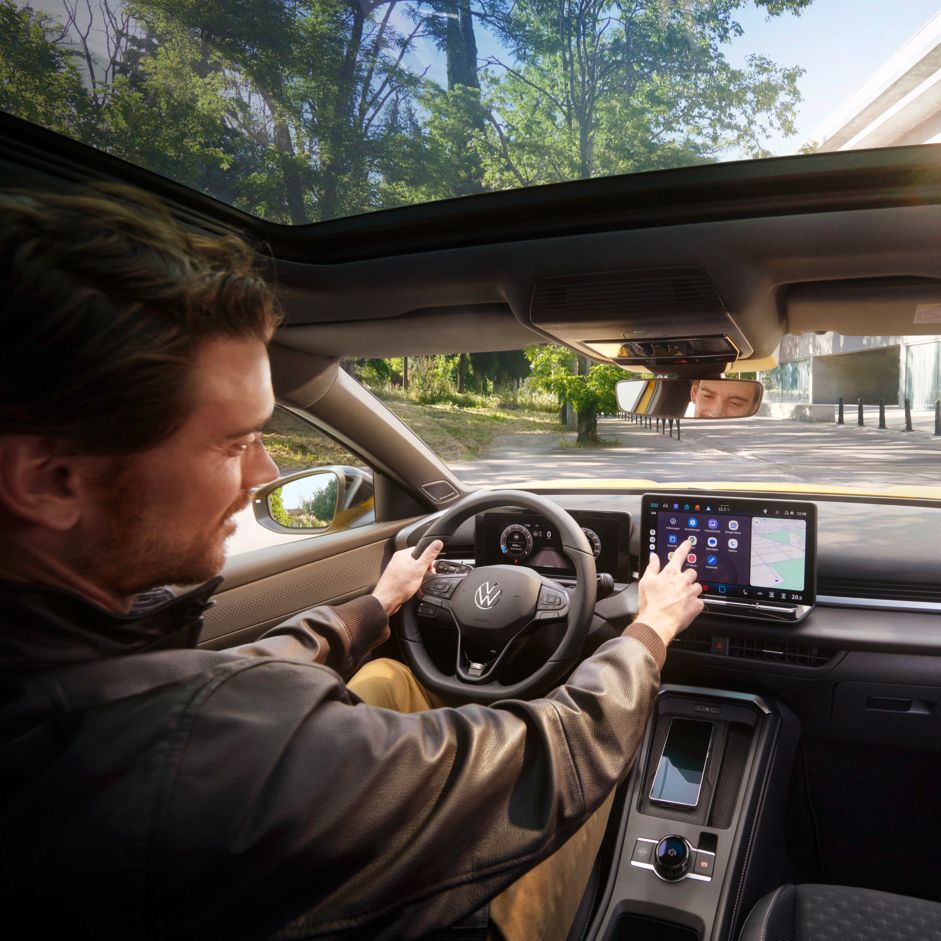 Ein Mann bedient auf dem Infotainment-Display in seinem Volkswagen T-Roc Android Auto über die App-Connect Schnittstelle.