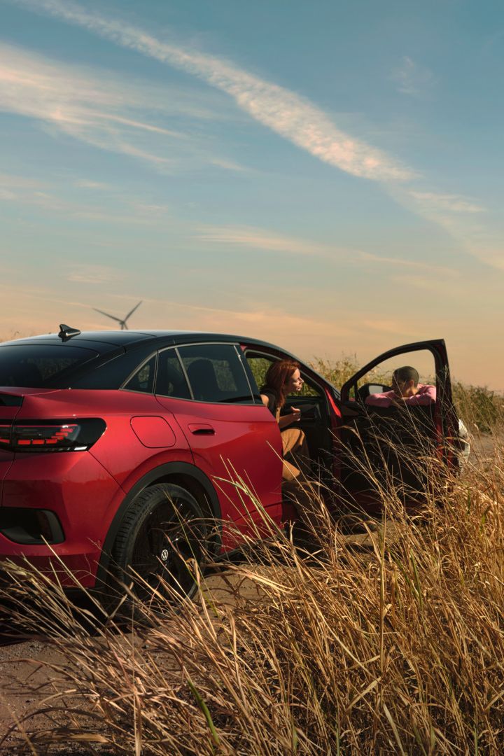 Zwei Personen unterhalten sich neben einem roten ID.5 GTX auf einer Landstraße