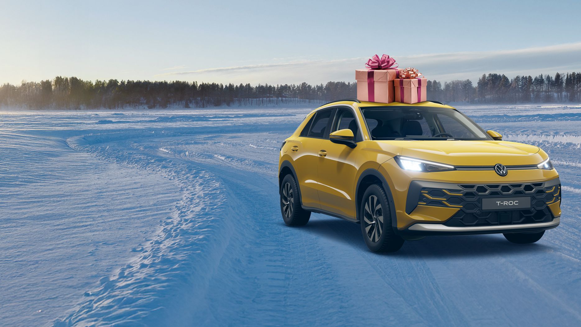 Ein gelbes Auto fährt durch eine verschneite Landschaft bei Sonnenaufgang. Auf dem Dach des Autos befindet sich eine große Geschenkbox mit einer roten Schleife. Im Hintergrund sind Bäume im Schnee zu sehen.