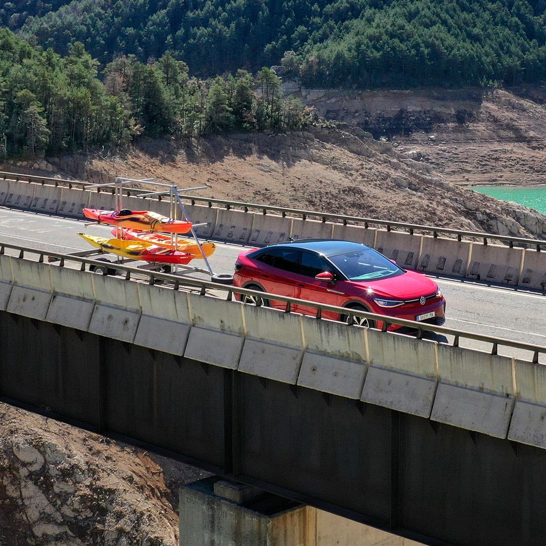 Ein roter ID.5 GTX fährt mit einem Anhänger über eine Brücke