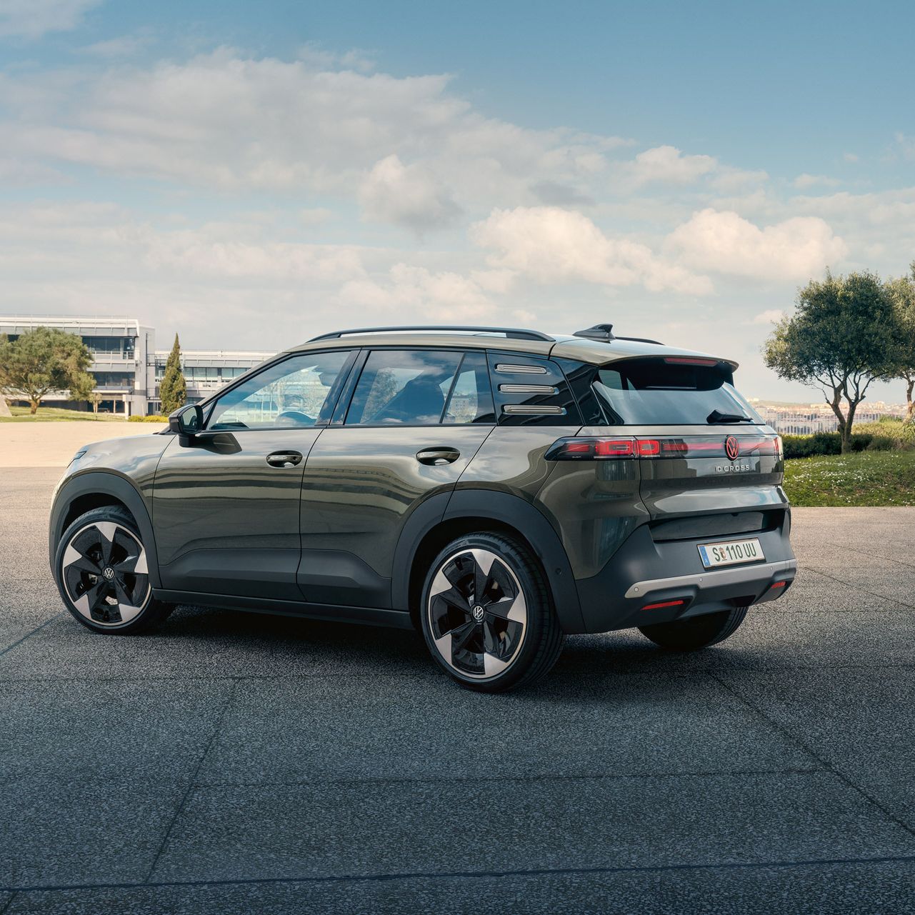 Heckansicht eines grünen VW ID. Cross, der auf einem Platz mit grünen Bäumen parkt.