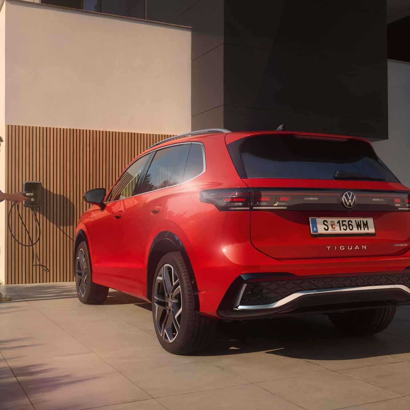 Ein Mann lädt seinen VW Tiguan R-Line eHybrid über seine Wallbox ID. Charger.