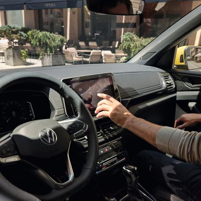 Ein Mann bedient vom Beifahrersitz aus den Bildschirm des VW T-Cross