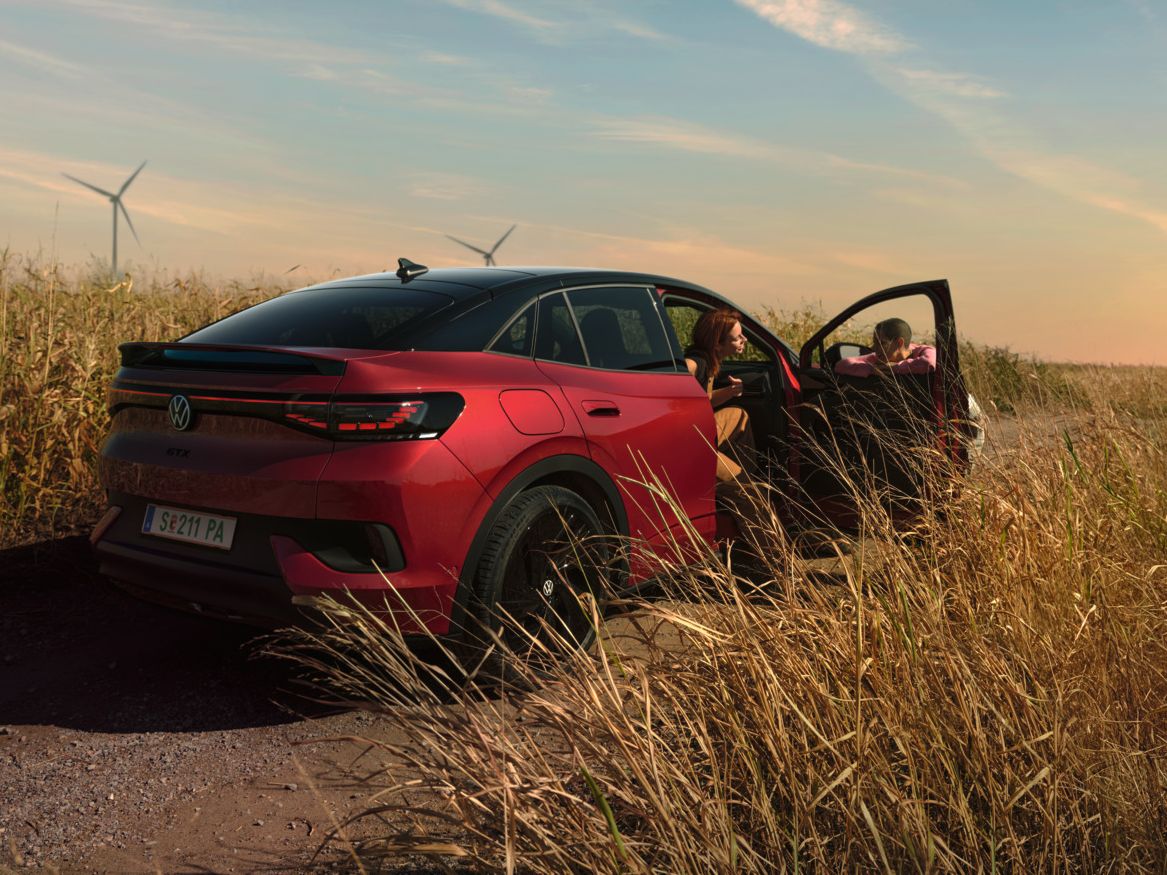 Zwei Personen unterhalten sich neben einem roten ID.5 GTX auf einer Landstraße