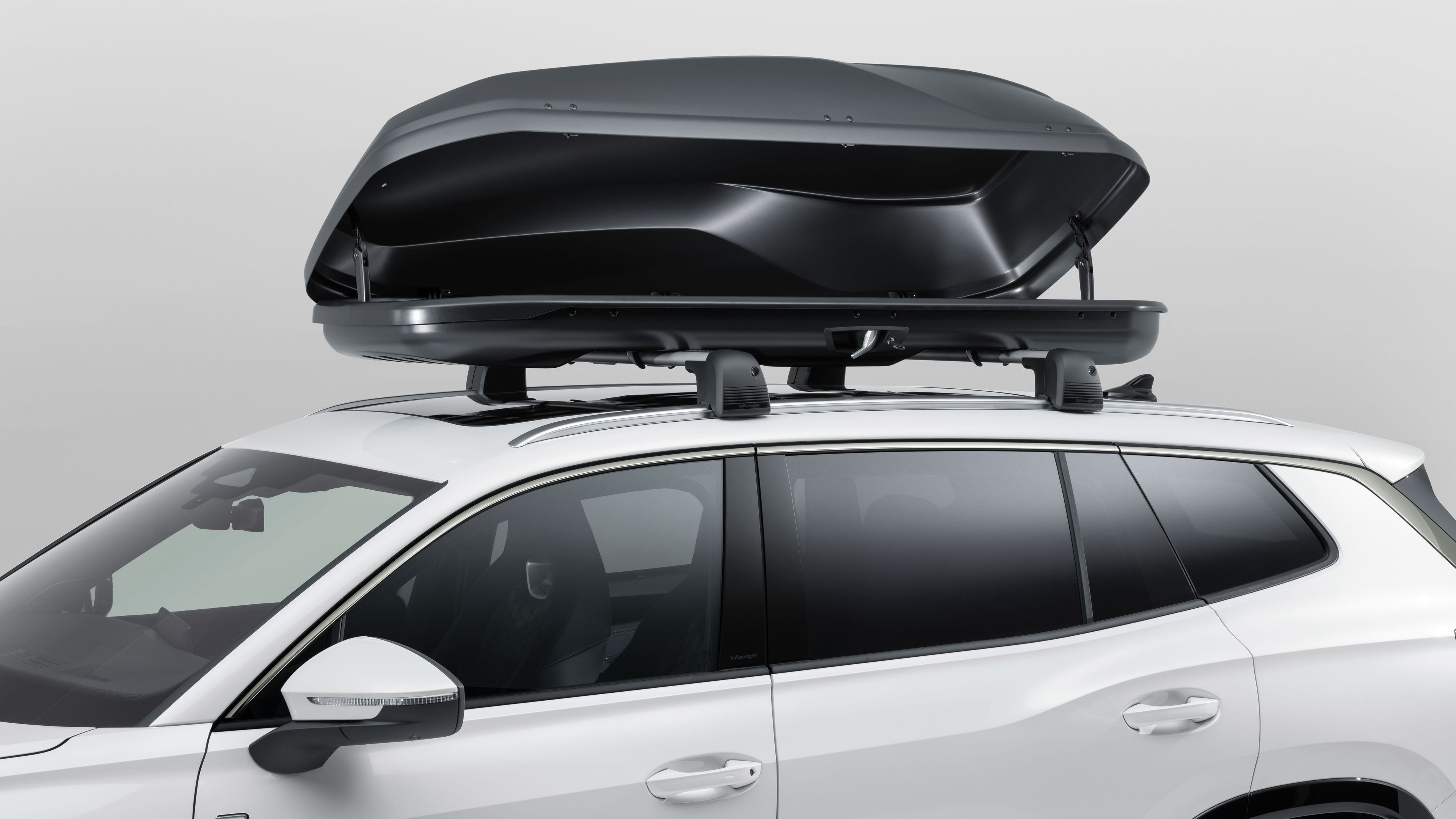 Eine geöffnete Volkswagen Dachbox auf dem Dach eines weißen Volkswagen.