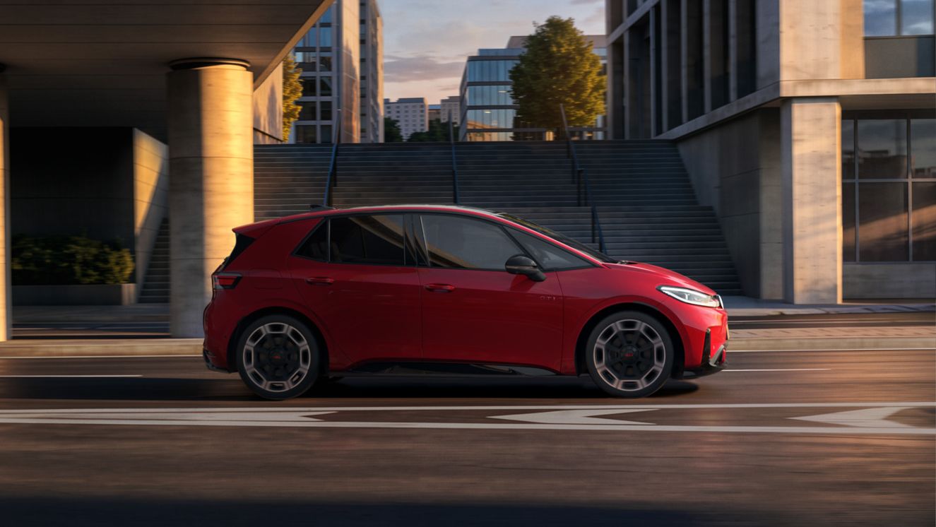 [AI-modified] – Seitenansicht eines roten VW ID.3 GTI während der Fahrt unter einer Brücke in der Stadt.
