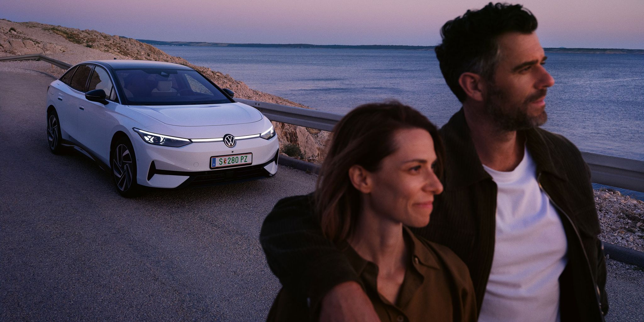 Ein Pärchen läuft am Meer entlang, im Hintergrund parkt ein ID.7 