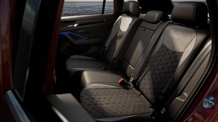 Der Innenraum von einem Tiguan mit luxuriösen Ledersitzen. Die Rückbank ist gut gepolstert und bietet ausreichend Platz für drei Personen. Im Hintergrund ist das Meer sichtbar.