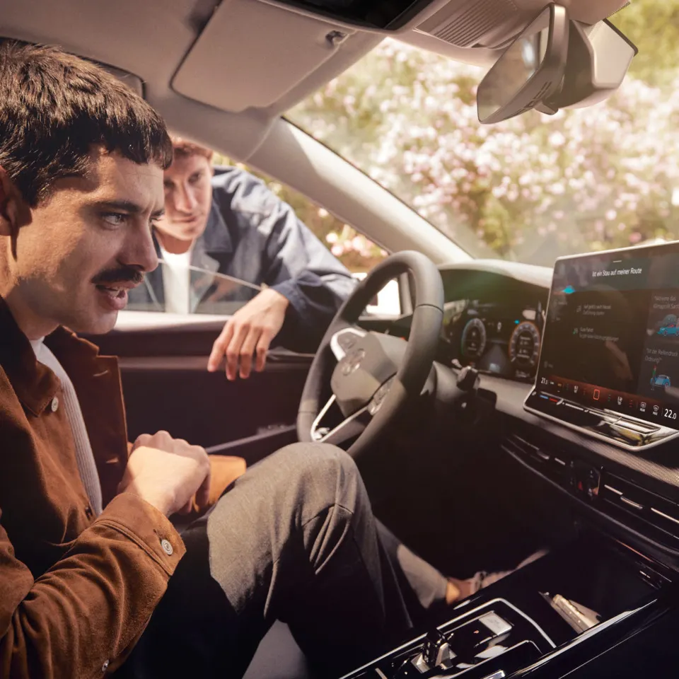 Zwei junge Männer nutzen den Sprachassistenten im VW Golf.