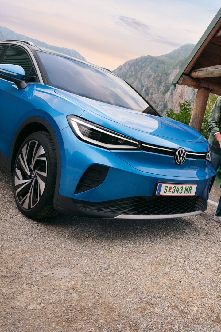 Vater und Sohn spielen mit einem Ball, daneben steht ein blauer VW ID.4.