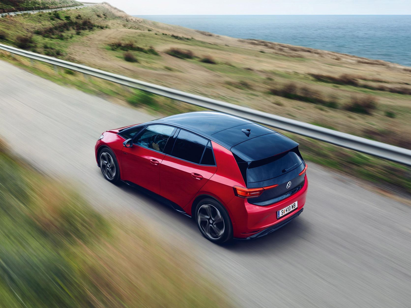  Ein roter VW ID.3 GTX fährt über eine Landstraße, im Hintergrund ist das Meer zu sehen.