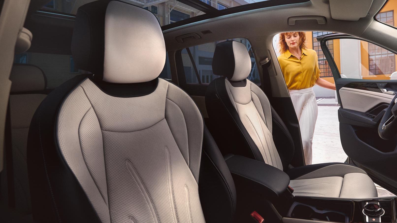 Innenansicht eines VW Tiguan mit Panoramadach und weißen Sitzen, Frau öffnet Fahrertür