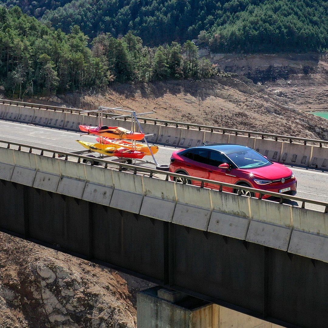 Ein roter ID.5 GTX fährt mit einem Anhänger über eine Brücke