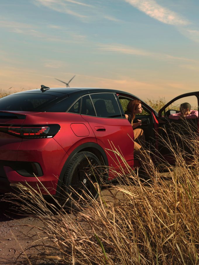 Zwei Personen unterhalten sich neben einem roten ID.5 GTX auf einer Landstraße